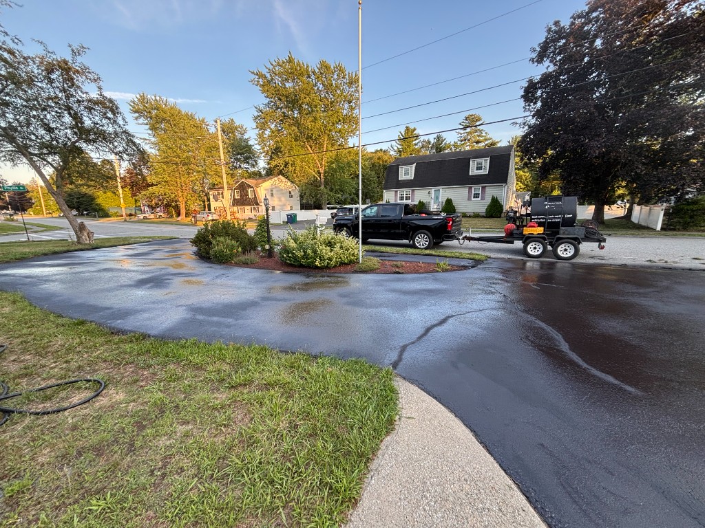 Large curved driveway sealcoated with professional equipment on site